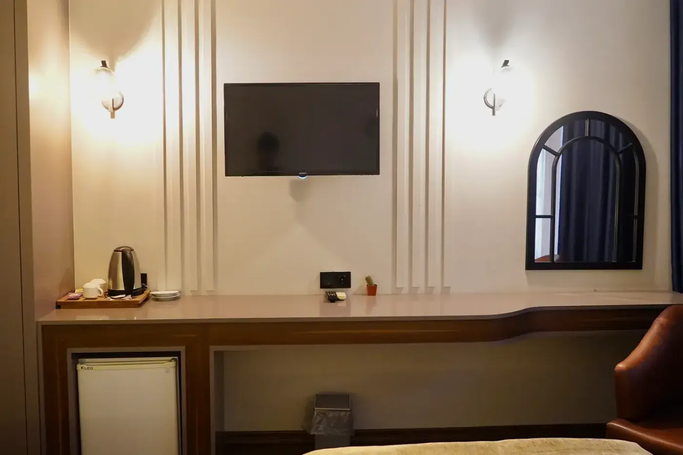 Deluxe Twin Oda’da duvara monte televizyon, uzun çalışma tezgâhı, su ısıtıcısı ve altta mini buzdolabı