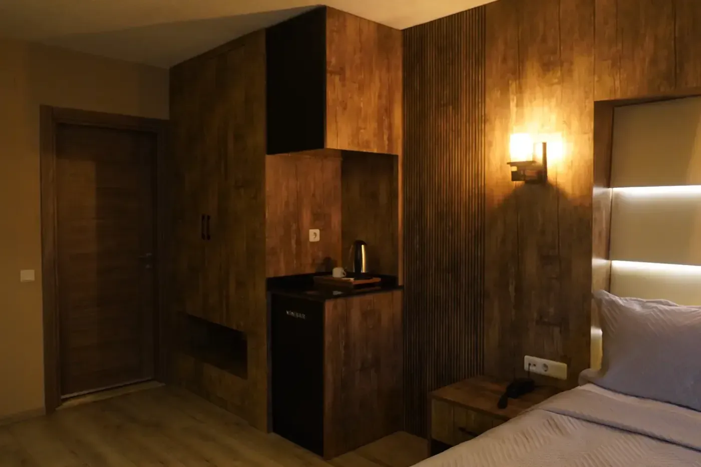 Junior Suit’te ahşap dolap duvarı; minibar ve su ısıtıcısının durduğu niş